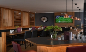 Bar mit Holztischen und Fernseher im Hintergrund