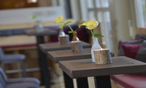 Hochtische mit kleinen Blumenvasen und Polsterbänken