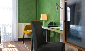 Schreibtisch mit Stuhl und gelber Lampe im Hotelzimmer