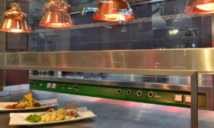 Essensausgabe mit Wärmelampen und angerichteten Tellern.