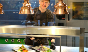 Koch richtet Teller an unter Wärmelampen.