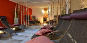 Ruhebereich mit Liegen, roter Wand und Naturdeko