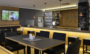 Moderner Gastraum mit Bar, Fernseher und dunkler Einrichtung