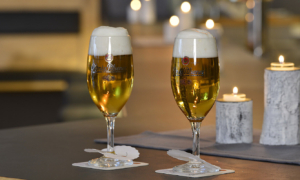 Zwei Biergläser mit Schaum und Kerzen auf dem Tisch