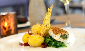 Hauptgericht mit Gemüse, Soße und Deko auf dem Teller.