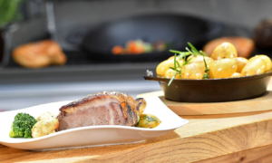 Teller mit Braten, Kartoffeln und Gemüse am Grill