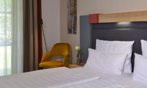 Landhotel-Schnuck-DZ-Komfort_0523_061 Teilansicht vom Bett mit gelbem Stuhl am Fenster