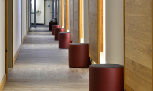 Hotelflur mit Holzverkleidung und roten Hockern