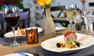 Tellergericht mit Wein und Blumenvase auf festlich gedecktem Tisch