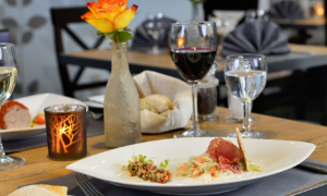 Gedeckter Tisch mit Wein, Stoffserviette und Blume im Restaurant.