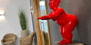 Rote Figur in Empfangsbereich mit Sessel und Pflanze