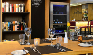 Restauranttisch mit Gläsern vor Bücherregal und Weinkühler