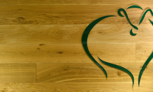 Grünes Logo auf Holzplatte in Form eines Herzens mit Hirschkopf