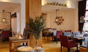 Landhotel-Schnuck_0722_054_Slider_7b70919421 Helles Restaurant mit gedeckten Tischen und Wandbildern