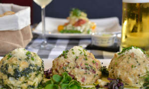 Dreierlei Knödel mit frischen Kräutern auf weißem Teller