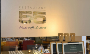 Schriftzug "Restaurant 55" über gedecktem Tisch im Eingangsbereich
