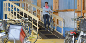 Frau schiebt ihr Rad über die Rampe in die Fahrradhalle