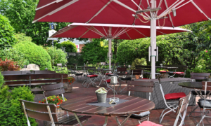 Schattige Terrasse mit roten Sonnenschirmen und Sitzplätzen