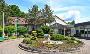 Rundbeet mit Skulptur vor dem Hoteleingang bei Tageslicht